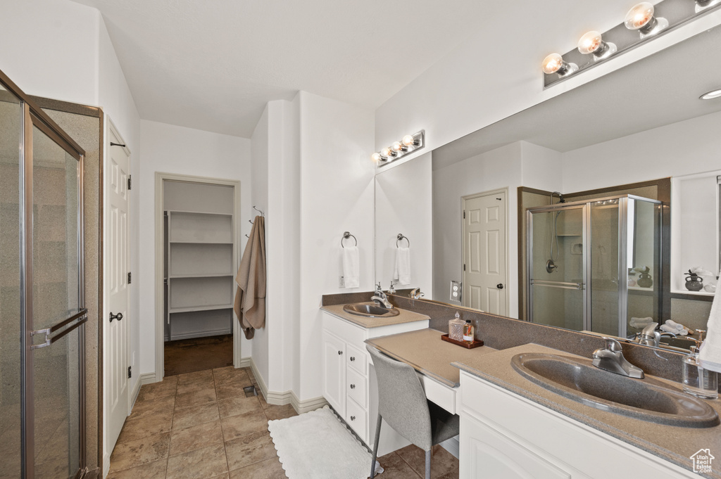 Full bathroom featuring double vanity, a shower stall, and a closet