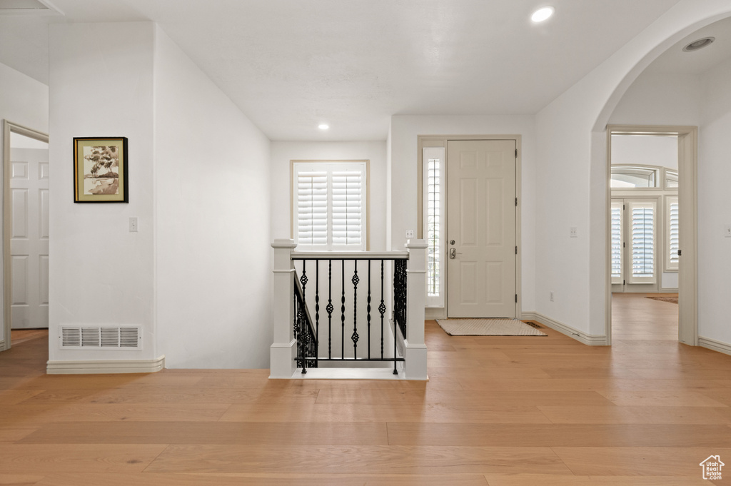 Entrance foyer with wood finished floors, arched walkways, and recessed lighting