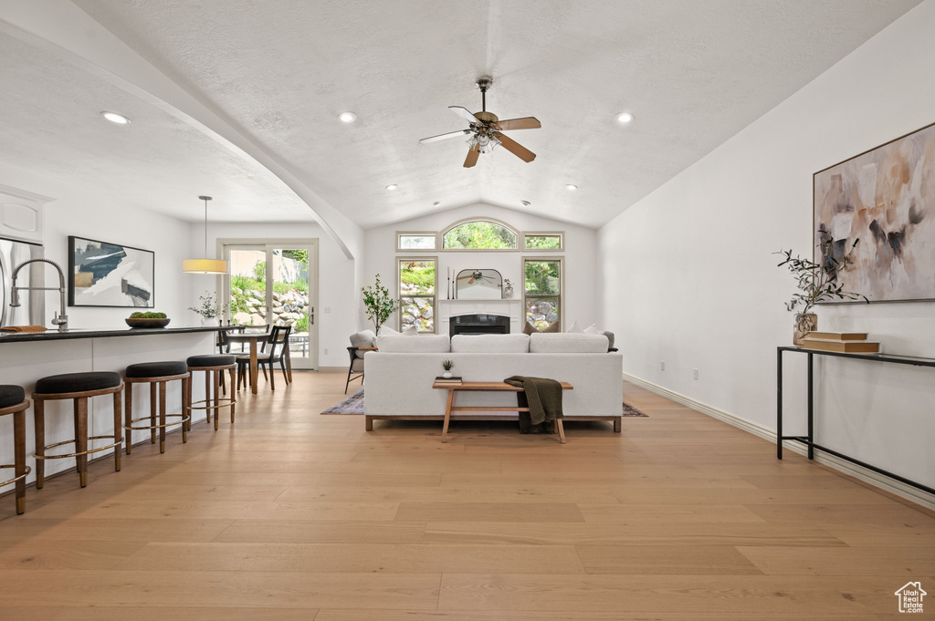 Living room featuring ceiling fan, lofted ceiling, light wood-style floors, and recessed lighting