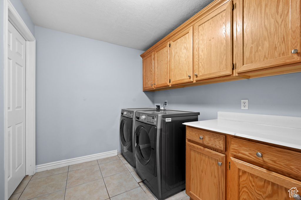 Laundry area featuring independent washer and dryer, cabinet space, and light tile patterned floors