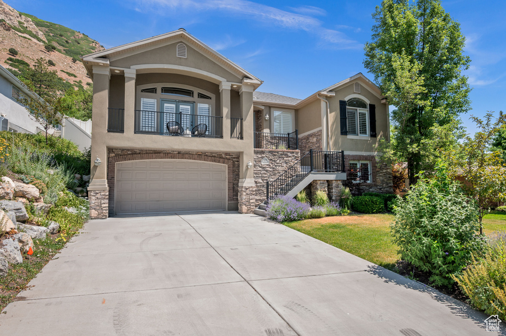 View of front of property featuring stucco siding, stone siding, and a garage