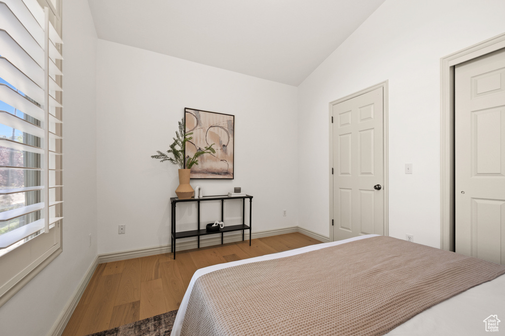 Bedroom featuring wood finished floors and vaulted ceiling