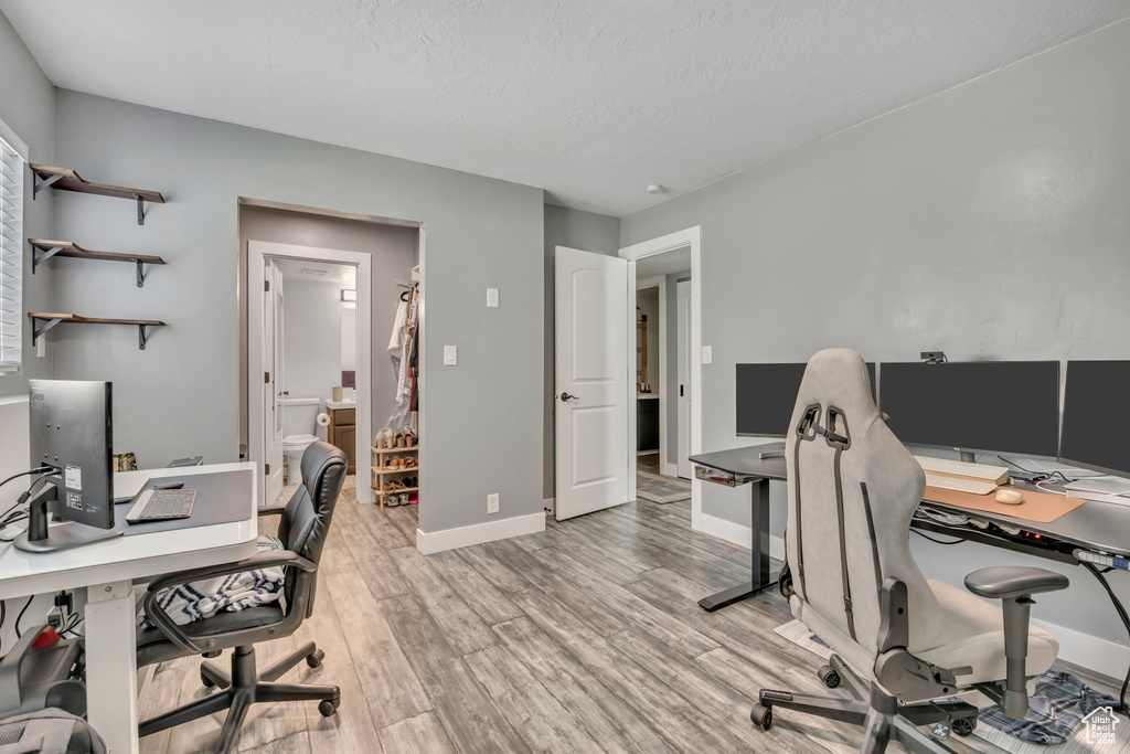 Home office with light wood-style flooring and a textured ceiling