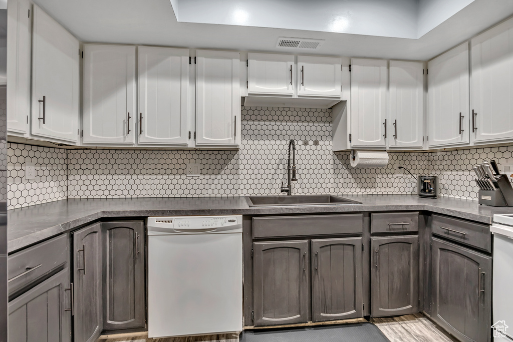 Kitchen featuring white dishwasher, tasteful backsplash, and dark countertops