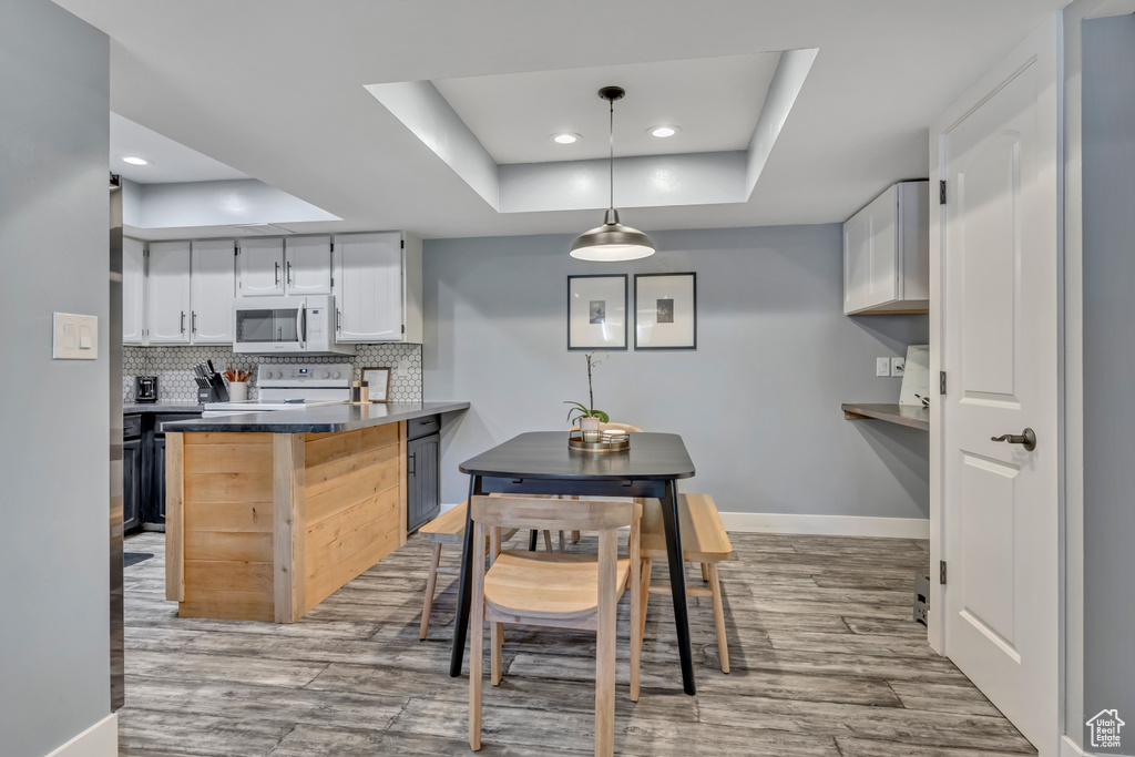Dining space featuring a tray ceiling, light wood-style floors, and recessed lighting