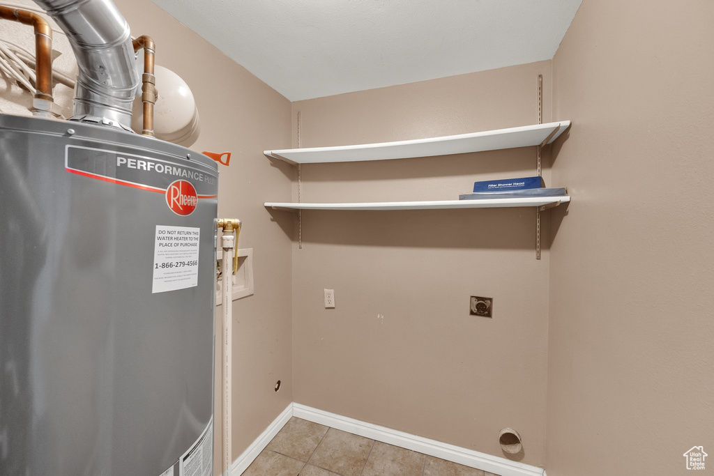 Washroom featuring electric dryer hookup, water heater, washer hookup, and tile patterned flooring