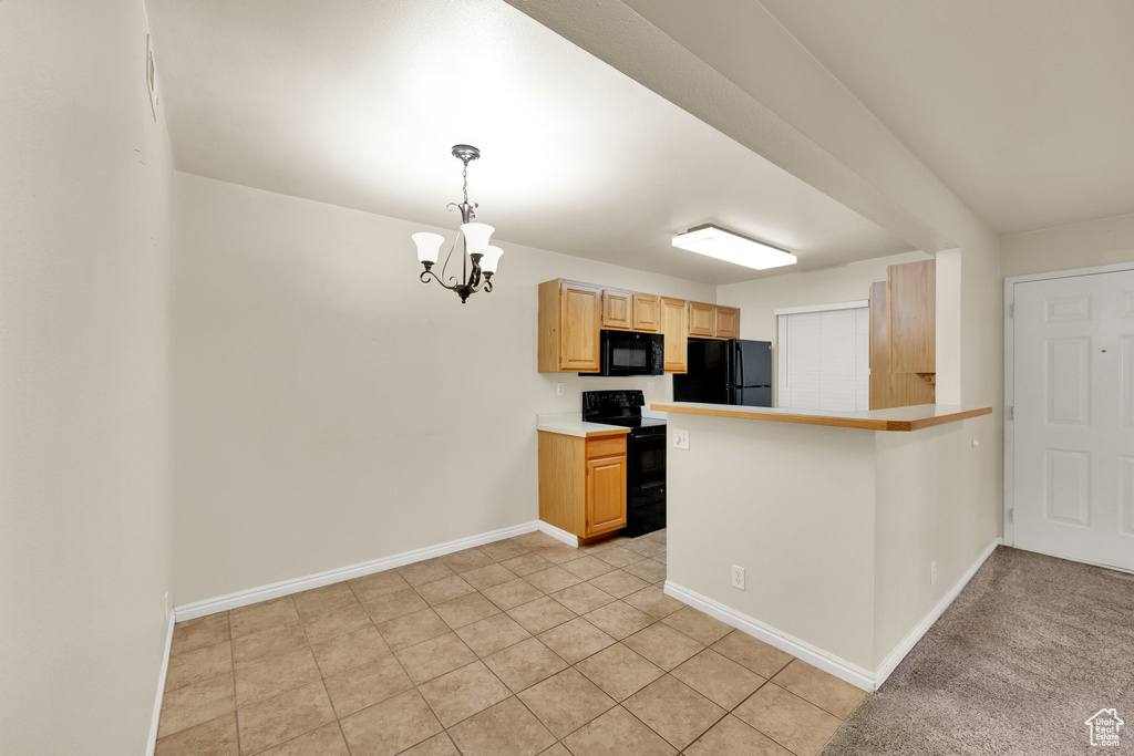 Kitchen with black appliances, pendant lighting, light brown cabinetry, light countertops, and a peninsula