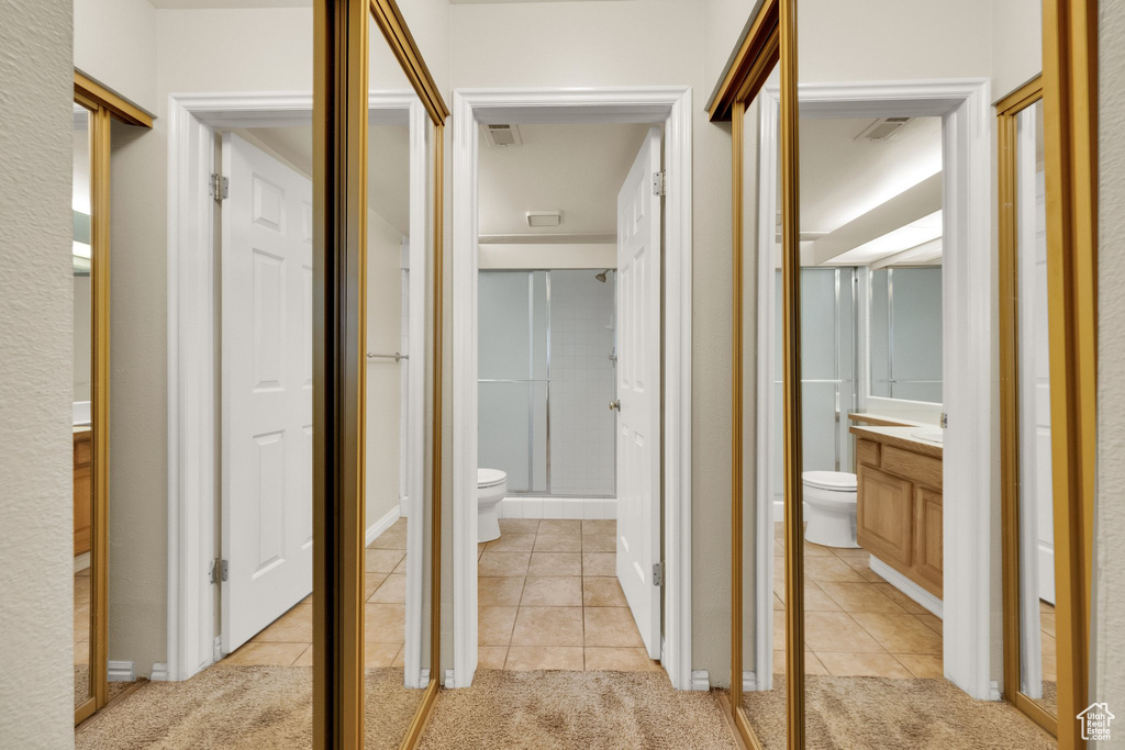 Hallway featuring light tile patterned floors and light carpet