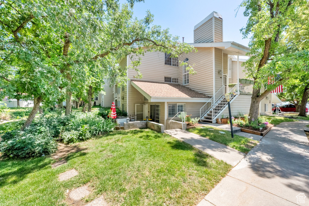 View of front of property featuring a front yard, a chimney, and stairway