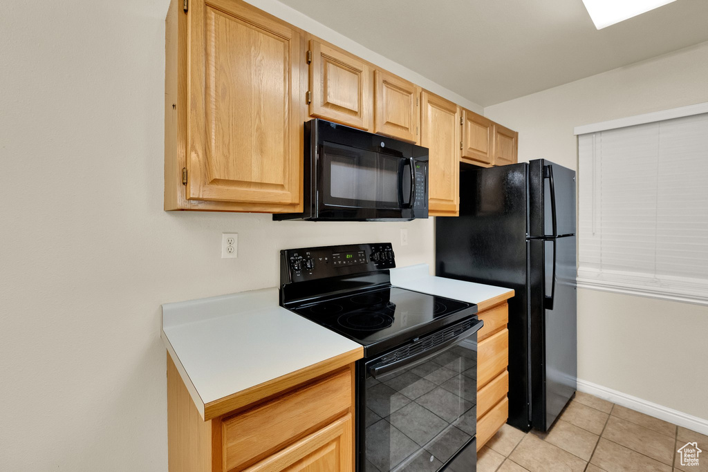 Kitchen featuring black appliances, light brown cabinets, light countertops, and light tile patterned flooring