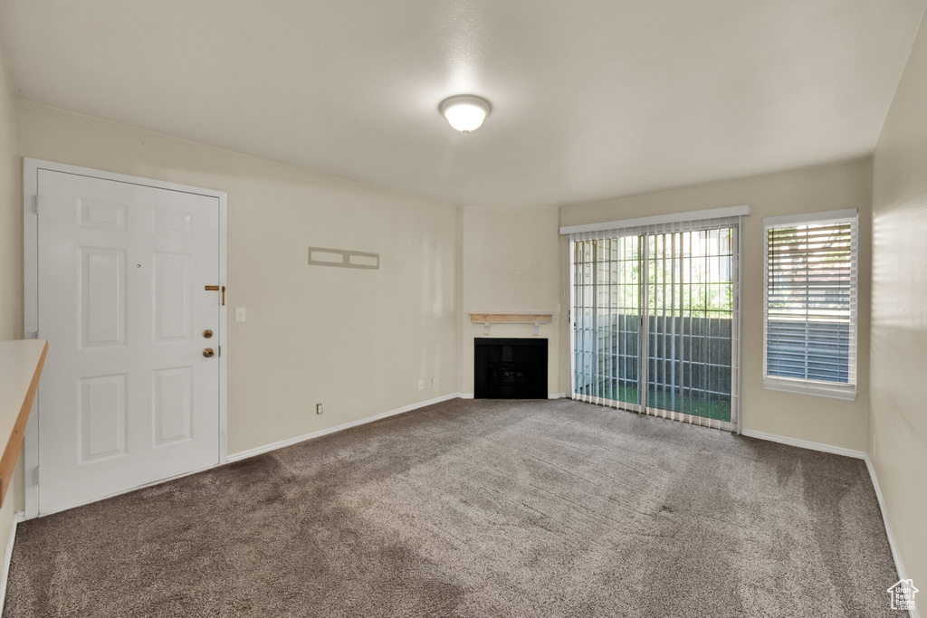 Unfurnished living room featuring carpet floors and a fireplace