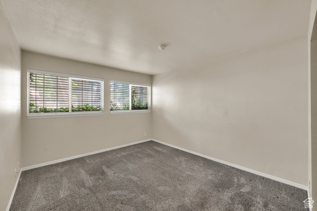 Empty room featuring dark carpet and a smoke detector
