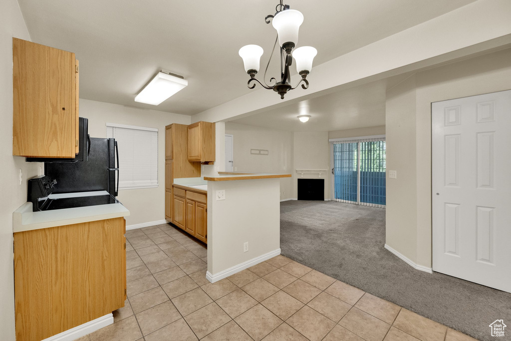 Kitchen featuring open floor plan, range with electric stovetop, light tile patterned floors, light countertops, and a chandelier