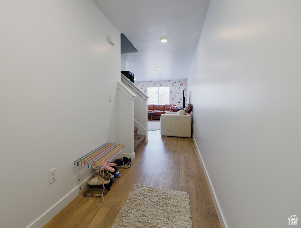 Hall with wood finished floors and stairway