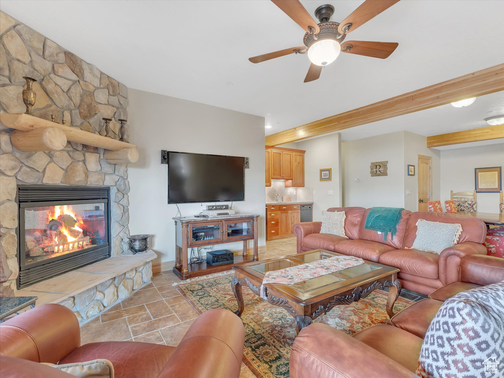 Living area featuring a ceiling fan, stone tile floors, and a fireplace