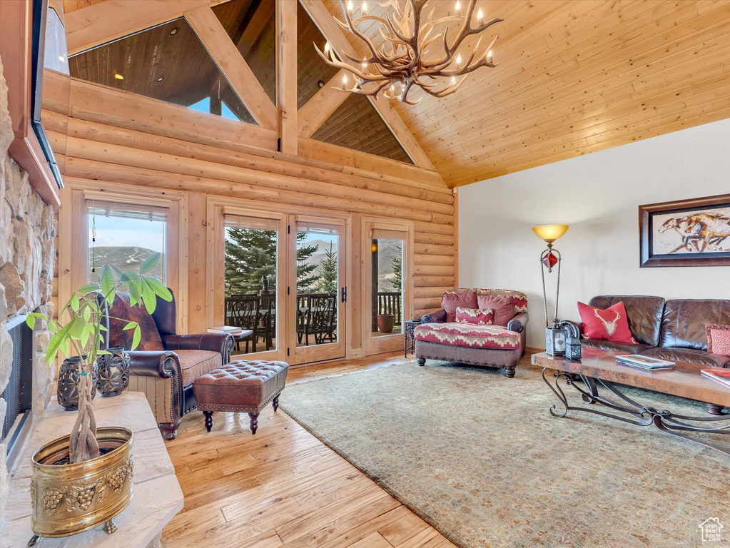 Living area with high vaulted ceiling, a chandelier, rustic walls, wood ceiling, and hardwood / wood-style flooring