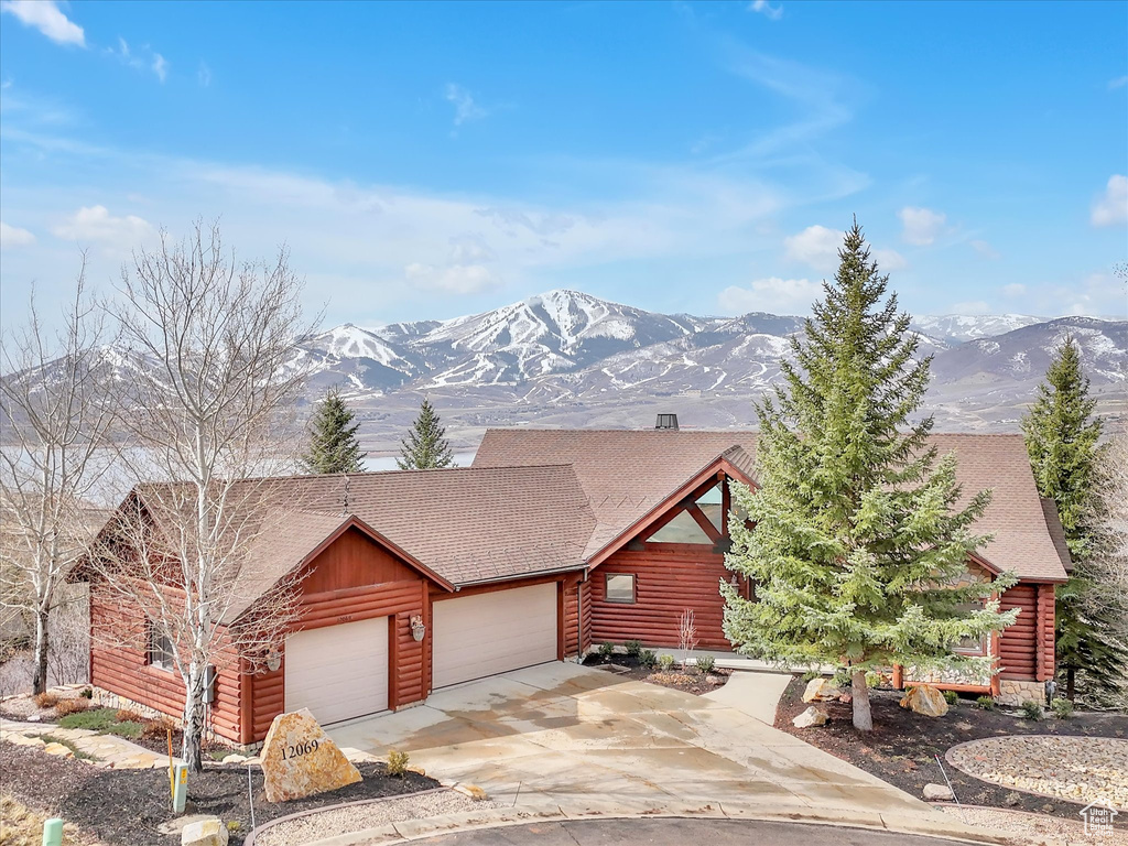 Log-style house with a garage, a mountain view, and driveway