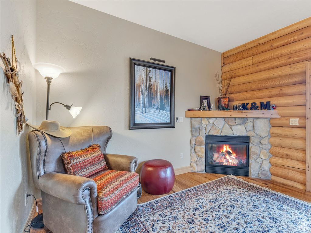 Living area with rustic walls, a stone fireplace, and wood finished floors