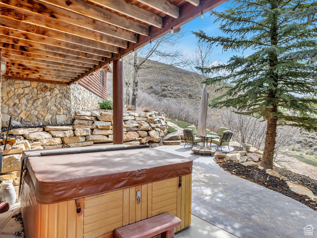 View of patio / terrace featuring a hot tub and a mountain view