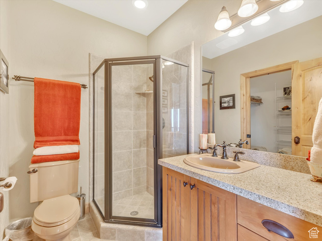 Full bathroom with a stall shower, vanity, a spacious closet, and tile patterned floors