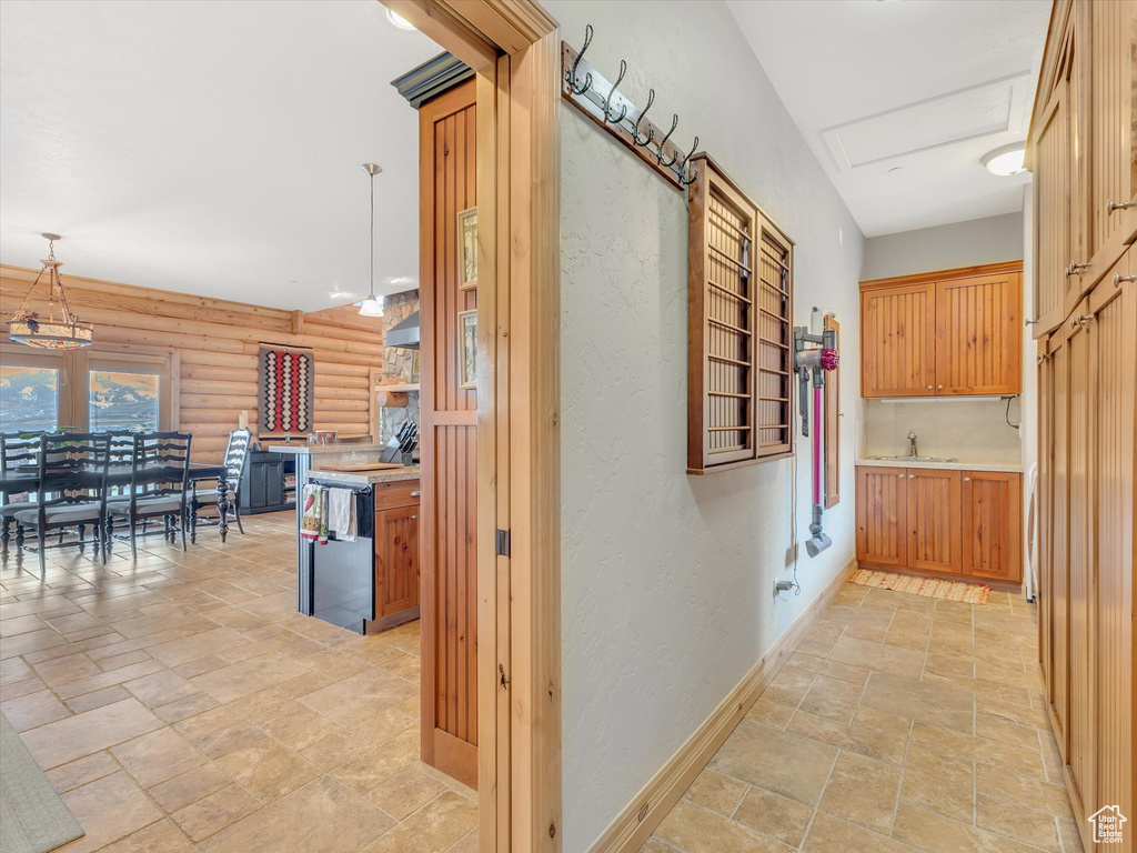 Hallway with stone tile flooring, log walls, and a textured wall