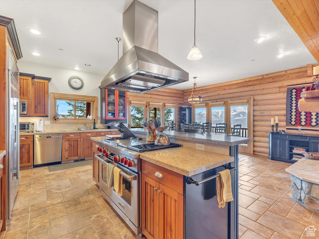 Kitchen with island range hood, stainless steel appliances, log walls, stone tile floors, and recessed lighting