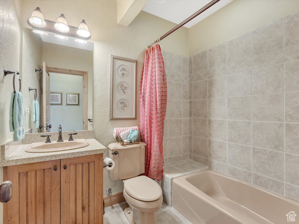 Full bath featuring shower / tub combo, vanity, and a textured wall