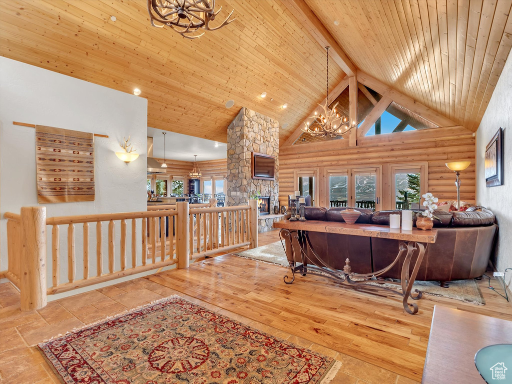 Living room with a chandelier, log walls, high vaulted ceiling, and a wooden ceiling with exposed beams