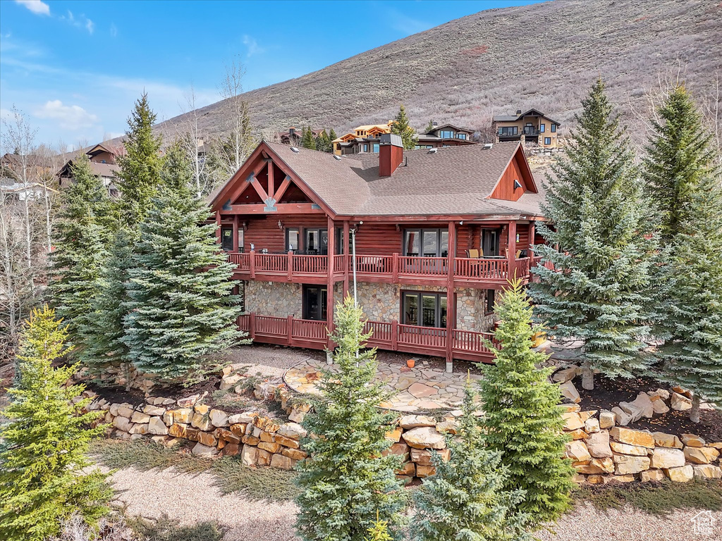 Back of property featuring stone siding, a balcony, french doors, and a deck with mountain view