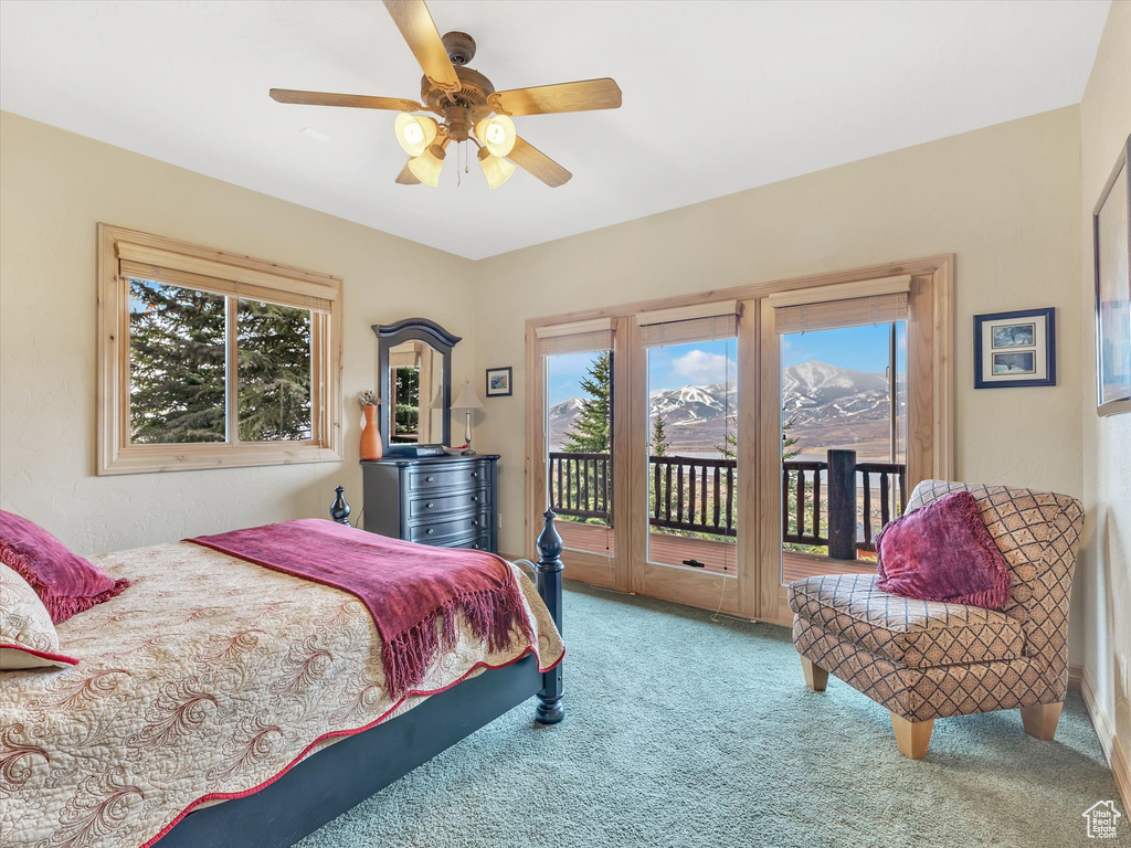 Carpeted bedroom with access to outside, multiple windows, a ceiling fan, and a mountain view