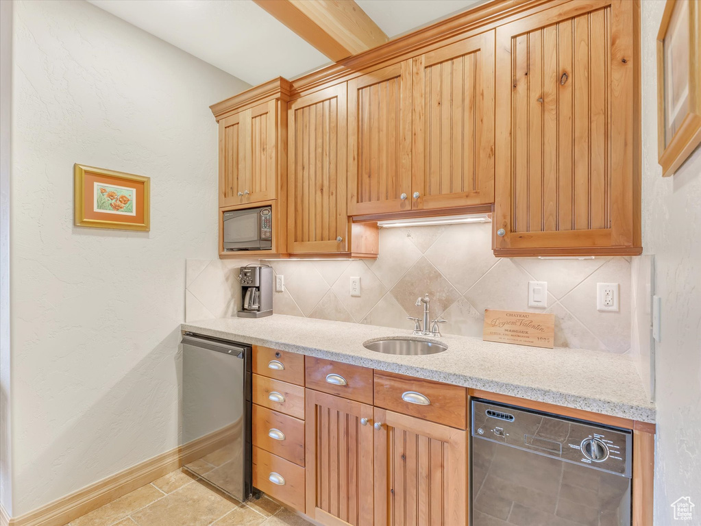 Kitchen with dishwashing machine, black microwave, tasteful backsplash, light stone countertops, and light tile patterned floors