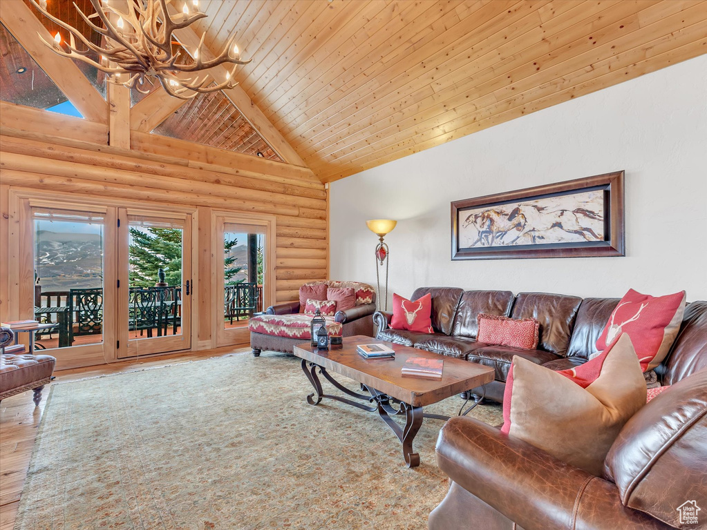 Living room featuring log walls, high vaulted ceiling, wood finished floors, wood ceiling, and a chandelier