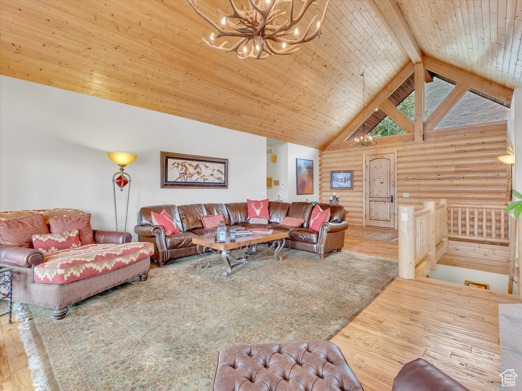 Living room with a chandelier, wood finished floors, log walls, high vaulted ceiling, and a wooden ceiling with exposed beams