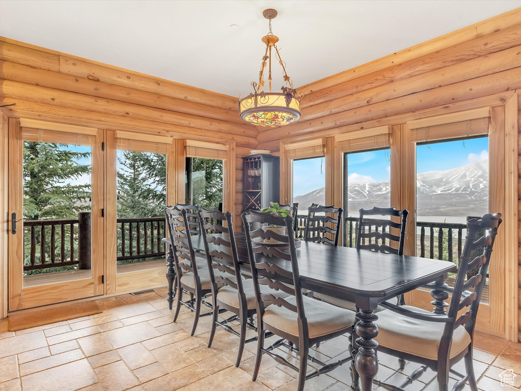 Dining room with stone tile floors, a mountain view, and log walls
