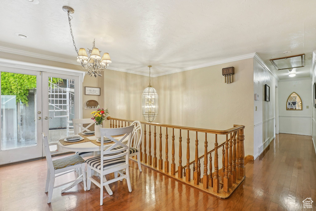 Dining room featuring a chandelier, wood-type flooring, crown molding, and attic access