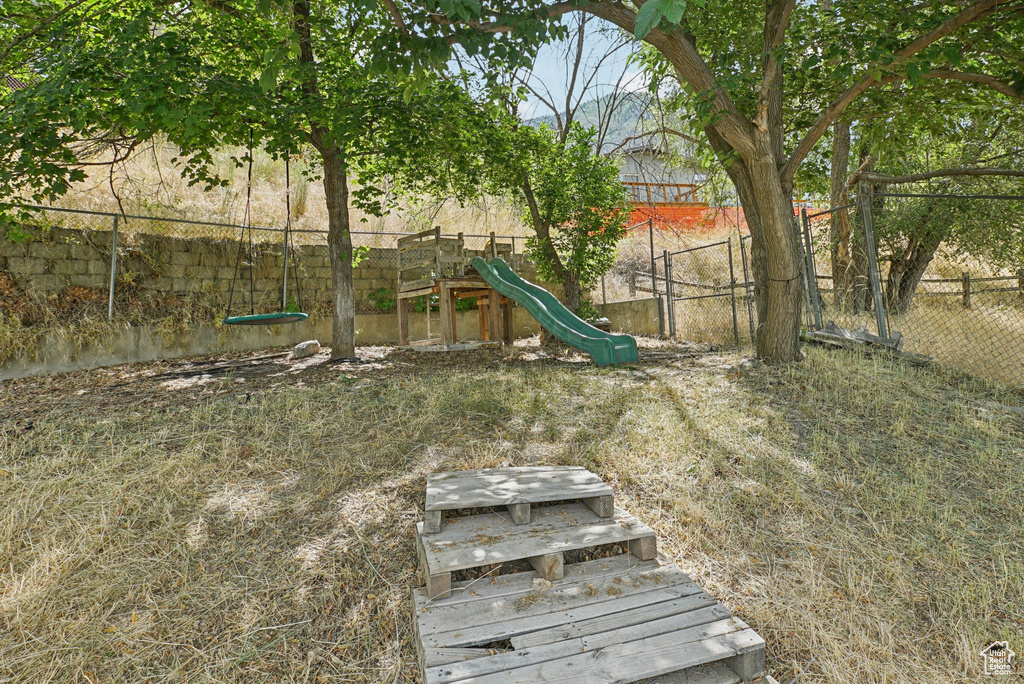 Fenced backyard featuring a playground