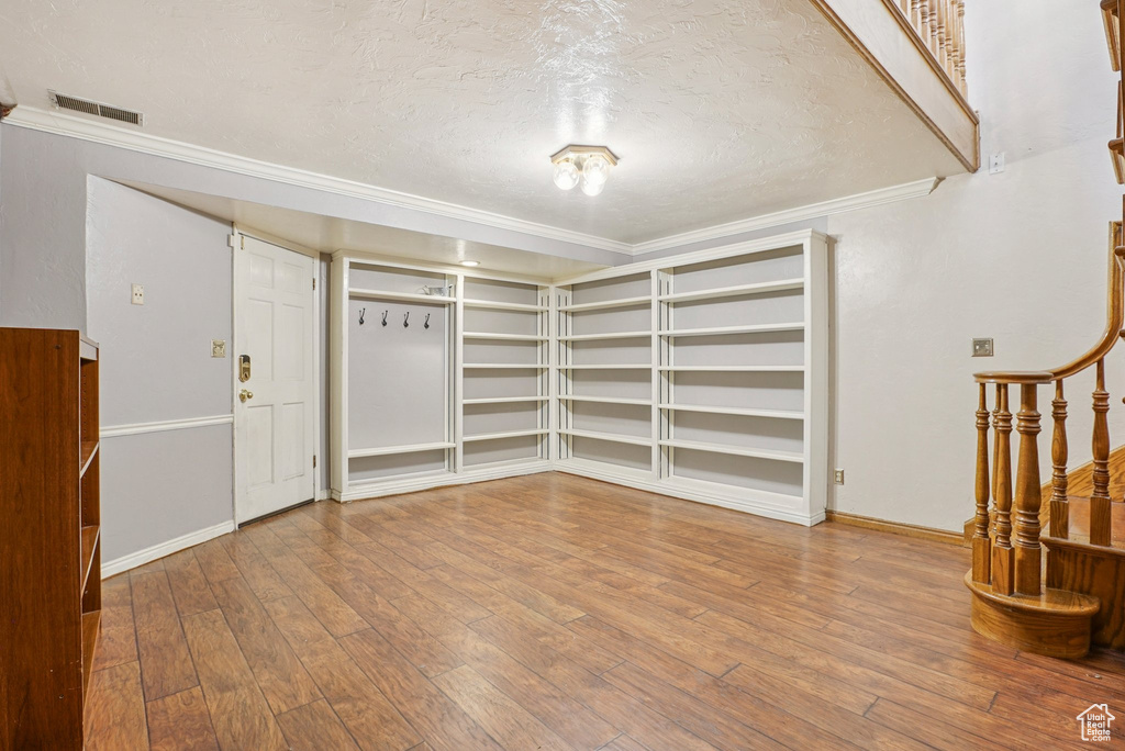 Unfurnished room with a textured ceiling, ornamental molding, hardwood / wood-style floors, and stairway