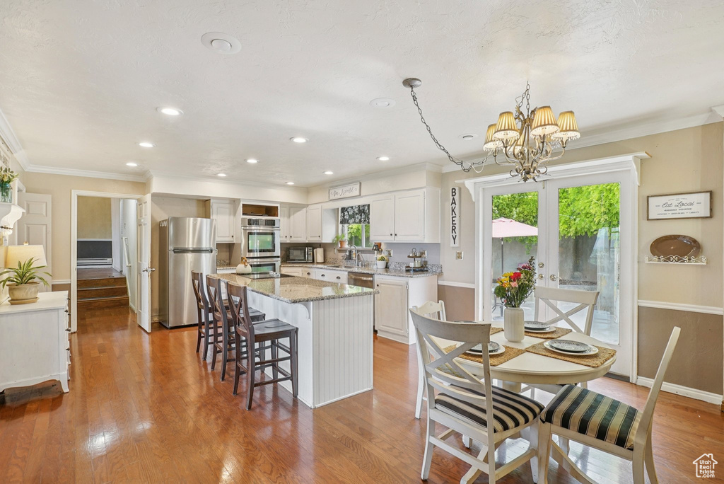 Dining room with a chandelier, ornamental molding, wood finished floors, and recessed lighting