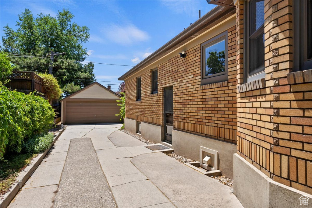 View of property exterior featuring an outdoor structure, a detached garage, and brick siding