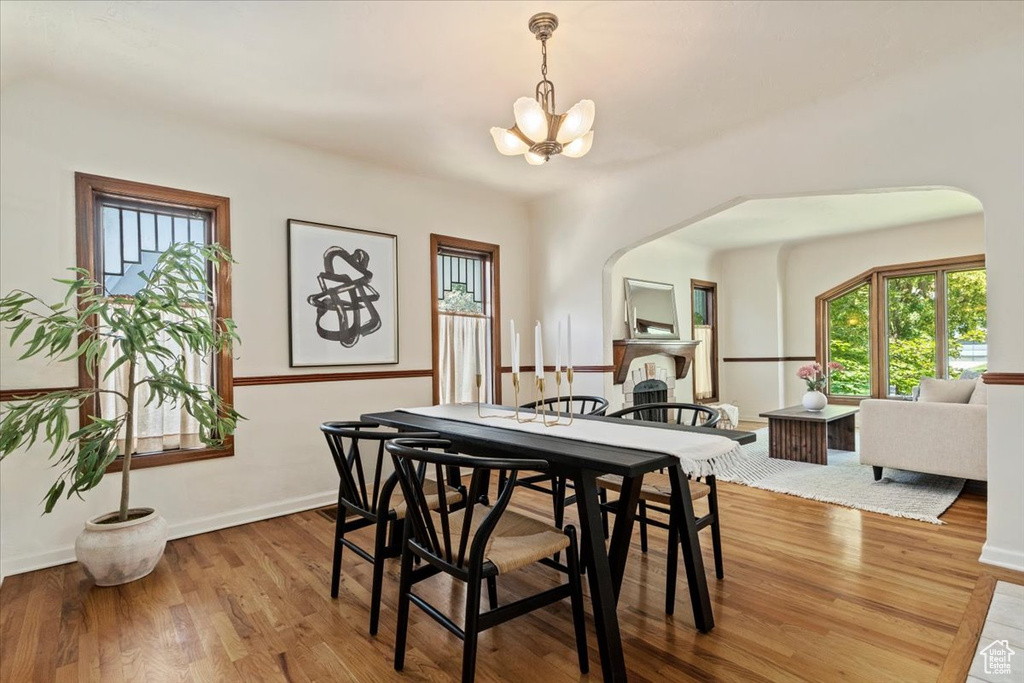 Dining room featuring a chandelier, plenty of natural light, wood finished floors, and arched walkways