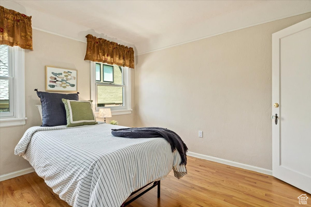 Bedroom with light wood finished floors and crown molding