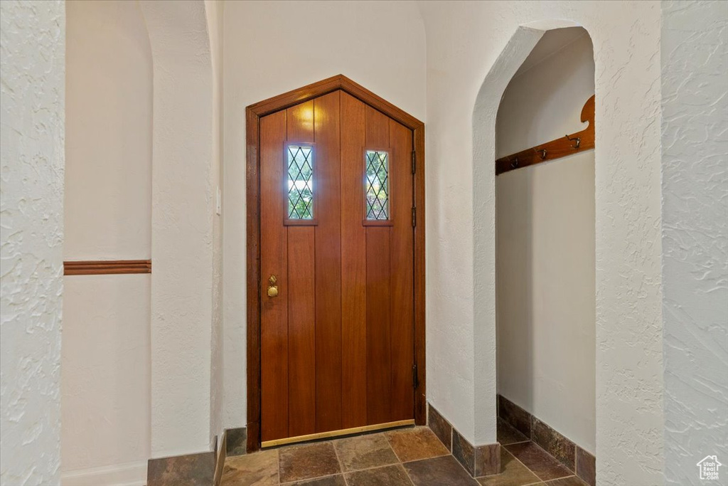 Foyer with a textured wall and stone tile flooring