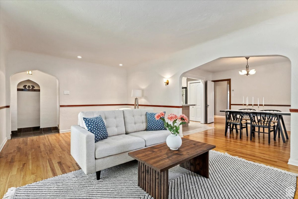Living area with arched walkways, light wood finished floors, and a chandelier