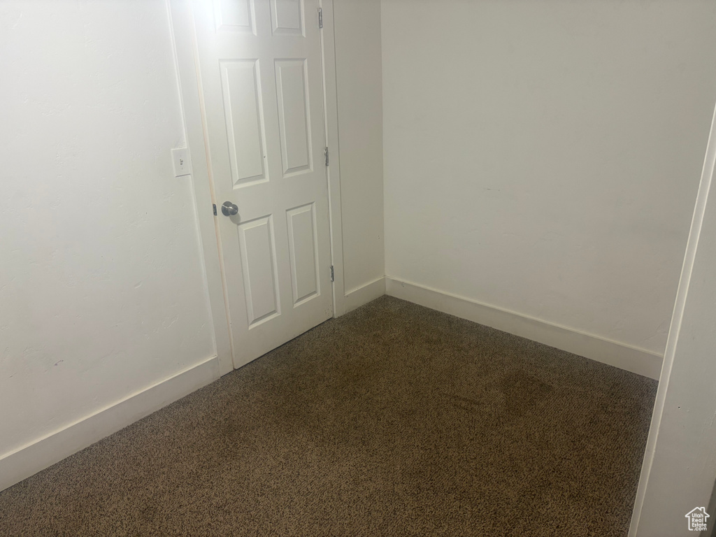 Empty room with dark colored carpet and baseboards