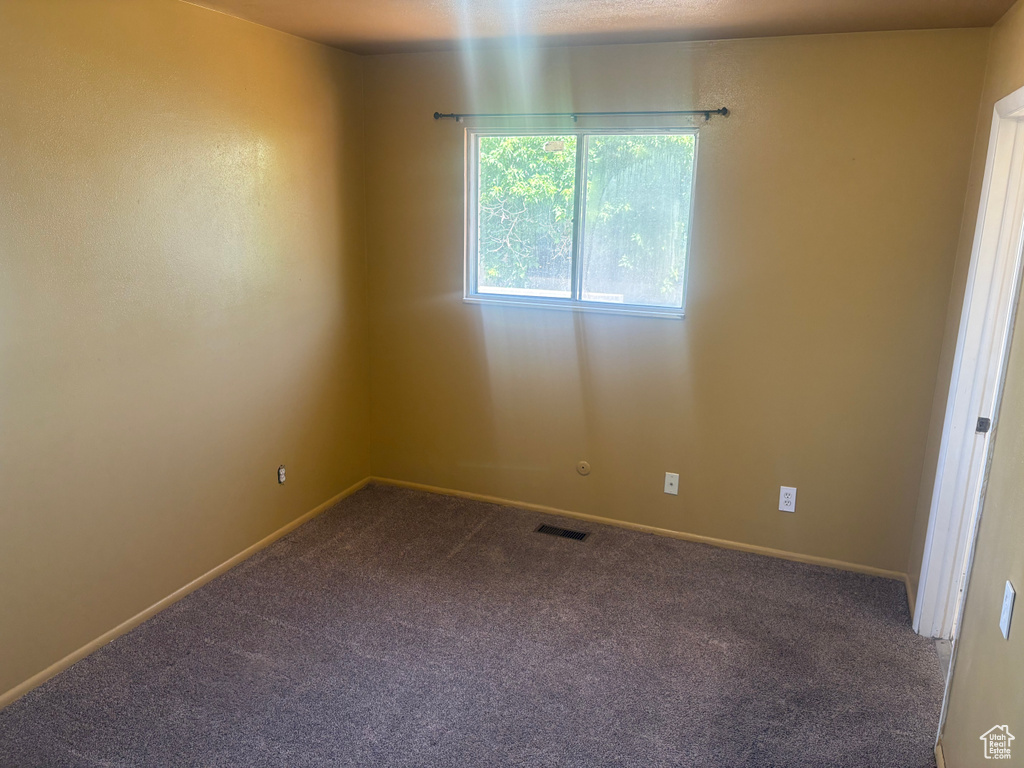Carpeted spare room featuring baseboards