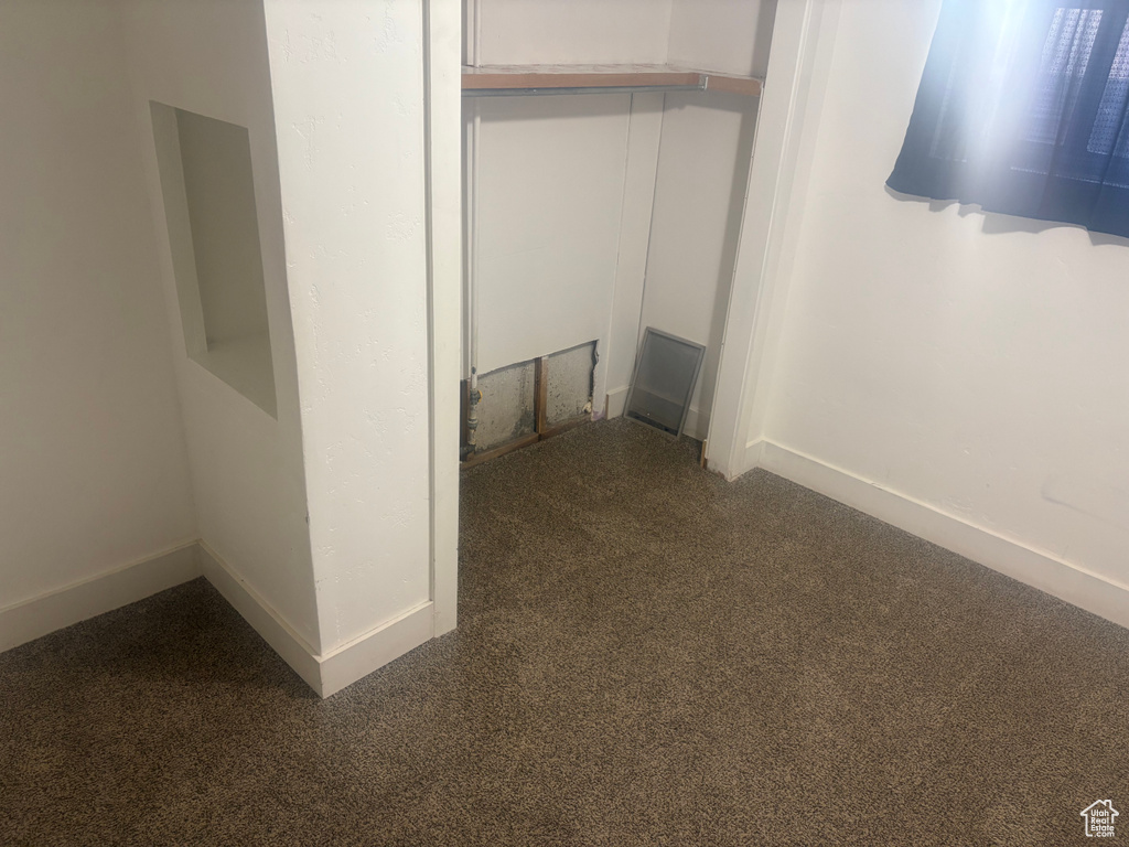 Hallway featuring baseboards and dark carpet