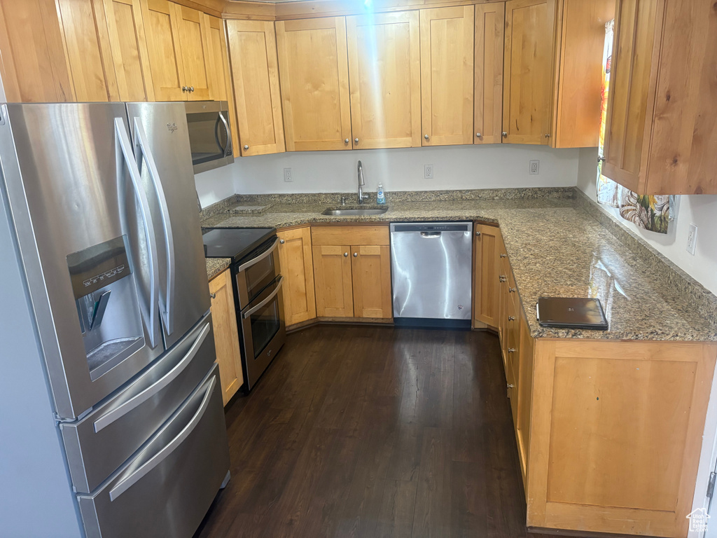 Kitchen with appliances with stainless steel finishes, dark wood-type flooring, and light stone countertops