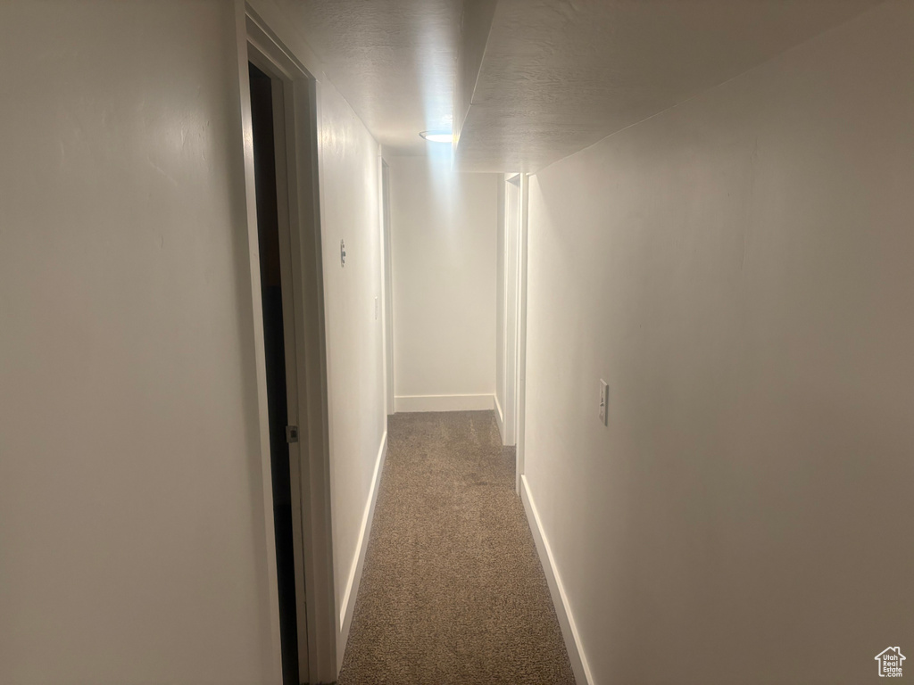 Hall featuring dark carpet and baseboards