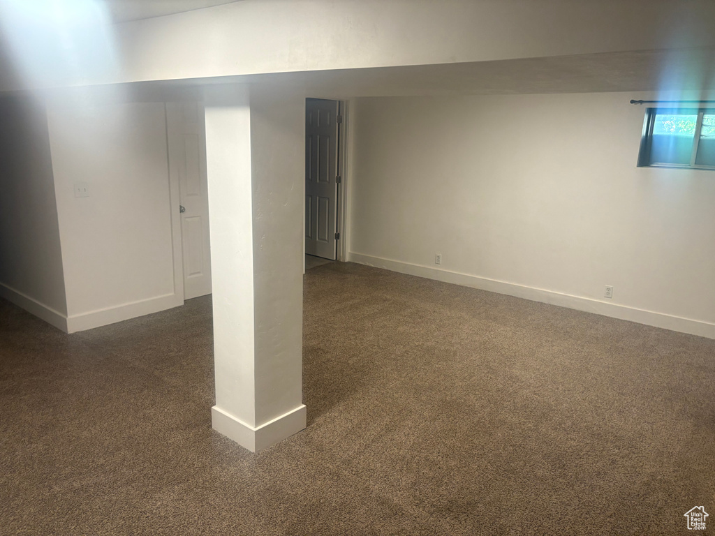 Below grade area with baseboards and dark colored carpet
