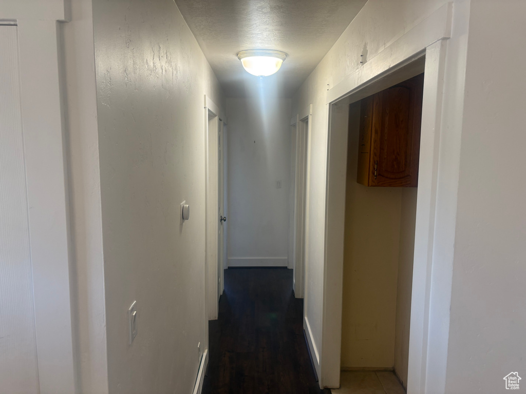 Hallway featuring a textured ceiling and baseboards
